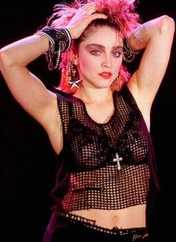 Madonna in the 80s wearing mesh vest, floral lace bra and crucifix necklace